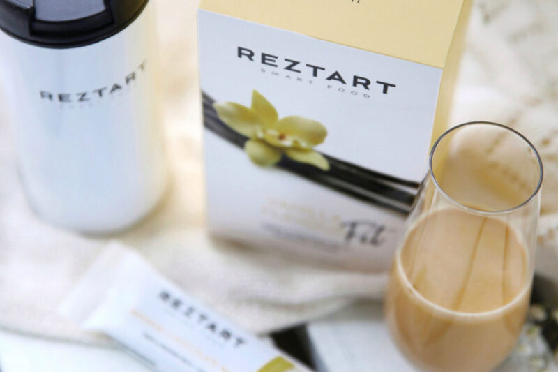 Reztart Vanilj Fit proteinshake – näringsdryck med vaniljsmak i glas, tillsammans med förpackning, bar och shaker.